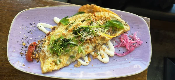 Gurme omleti, taze otlar, soslar ve renkli süslemelerle kaplıdır. Yemek pişirme sanatını ve sunumunu sunar..