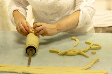 Koca göbekli domuz. Kadın hamuru ustalıkla hazırlıyor. Elleri yeni yapılmış makarna ve mutfak atmosferiyle çevrili.