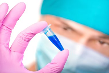 Maskeli genç adam dikkatle plastik tüp görünüyor