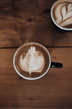 Bir fincan sıcak latte sanat kahvesi ahşap masada, beyaz köpüğe odaklan.