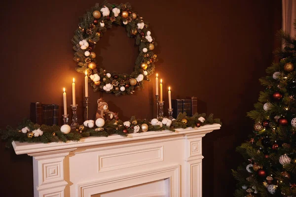 Christmas wreath above classical fireplace. Xmas scene. Place for text. Suitable for Christmas background. Above the fireplace hangs a wreath of spruce. New year design.