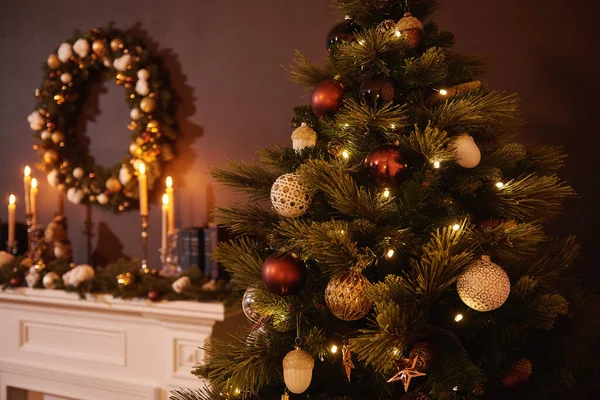 明亮的圣诞玩具挂在一棵绿树上 用金银花模糊了温暖的背景 圣诞树装饰圣诞树点亮的背景 点燃的蜡烛 新年的花环 — 图库照片