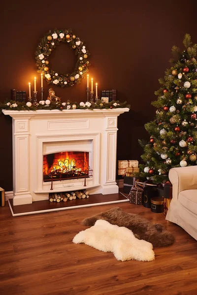 Fireplace and gifts under the Christmas glowing tree, vertical photo. Christmas home decor. Beautiful holiday decorated room with Christmas tree with presents under it. Xmas Home Interior Decoration