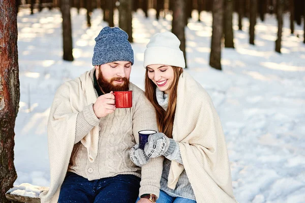 Kış parkında sıcak içeceklerle dolu güzel bir çiftin yan profil fotoğrafı beyaz bir ekoseyle kendilerini ısıtıyor. Kış tatili konsepti. Kış tatili, tatil, Kafkasya