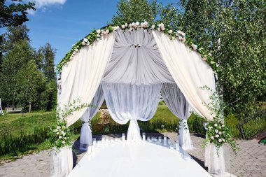 Evlilik kaydı için dekore edilmiş bölge. Canlı çiçekler, beyaz sandalyeler, mumlar, tekstil