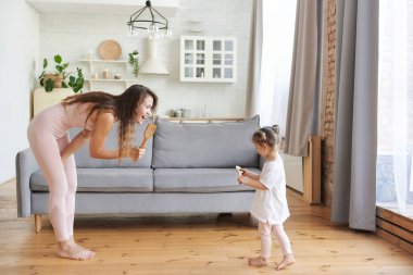 Neşeli genç anne ya da dadı tatlı küçük kız çocuğuyla oynarken eğleniyor, heyecanlı anne küçük kızla dans ediyor, heyecanlı çocukla eğlenceli çocuksu aktiviteler yapıyor hafta sonları evde.