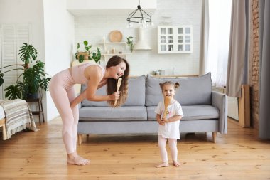 Harika bir ev partisi. Duygusal aile genç bekar anne ve küçük kızı yeni modern mutfakta müzik dinleyerek eğleniyorlar. Neşeli küçük kız dadı sıcak ahşap zeminde yalınayak zıplıyor.