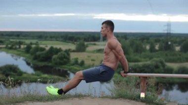 Tişörtsüz genç bir vücut geliştirici spor olsun diye içeri girer ve yedek kulübesinde şınav çekerek kol kaslarını sallar. Yan görüş. Yakın plan. Kamera aşağı yukarı hareket ediyor.