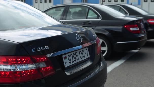 Minszk, Fehéroroszország - 2020. szeptember 17.: Egy tekintélyes Mercedes modell bemutatása. Fekete autók állnak sorban a demonstrációs területen háttal a kamerának. Közelkép — Stock videók