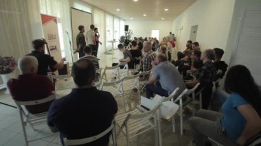 Minsk, Belarus - 17 Eylül 2020: Elinde bir mikrofon tutan ve bir grup insanla eğitim konferansında konuşan genç adam