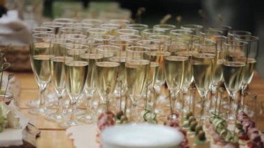 Gala etkinliği için abur cuburların yanındaki ahşap bir masada şampanya kadehleriyle yakın çekim. Kamera odağı değiştirir.