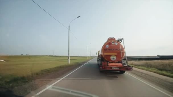 Rostov-on-Don, Rusia - 17 de septiembre de 2020: Vista a través del parabrisas de un automóvil conduciendo a lo largo de la carretera durante el día y adelantando a un gran camión de combustible naranja — Vídeo de stock