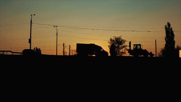 Tmavé siluety aut na pozadí večerní oblohy v liniích drátů na rušné silnici — Stock video