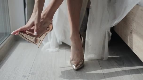 Zbliżenie nóg młodej panny młodej zakładającej piękne złote buty na obcasie podczas przygotowań do ceremonii ślubnej — Wideo stockowe