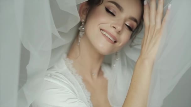 Ritratto di una sposa incredibilmente bella con un bel trucco e gioielli originali in un velo bianco vicino al viso — Video Stock