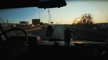 Şehrin varoşlarındaki işlek bir yolun ön camından ve gün batımına karşı bir otoyol çıkışından bak.