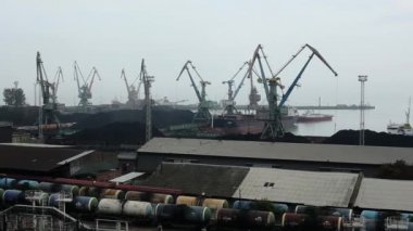 Büyük kule vinçleri denizde ve depolama sahalarında büyük kömür dağları ve petrol trenleri olan bir demiryolu ile çalışır.