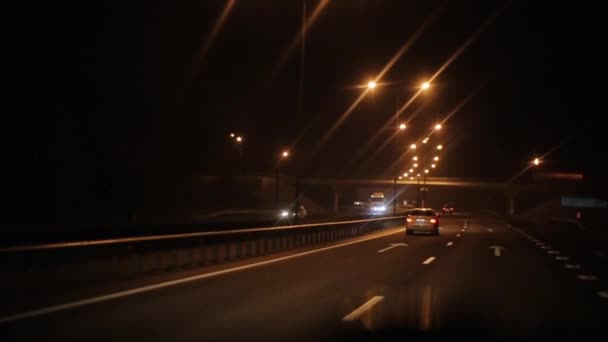 Drukke nachtelijke verkeer van verschillende voertuigen op de snelweg en een weg kruising met een brug. Wegrit — Stockvideo