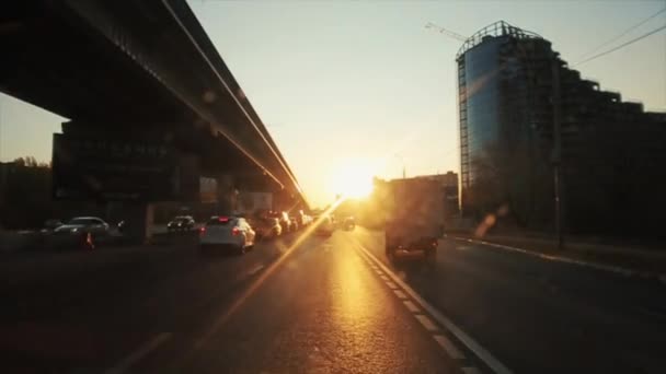 Rostov-on-Don, Russia - September 17, 2020: Busy traffic on the city road near the bridge against the background of the sunset and the building under construction — Stock Footage Rostov-on-Don, Russia - September 17, 2020: Busy traffic on the city road near the bridge against the background of the sunset and the building under construction Royalty Free Stock Video