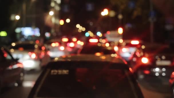 Luces borrosas multicolores de la ciudad nocturna desde la cabina de un coche conduciendo por una carretera concurrida — Vídeos de Stock