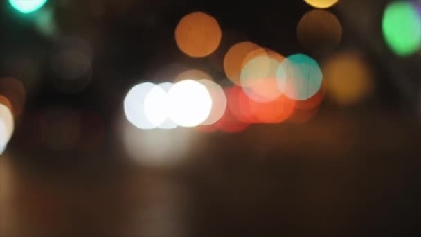 Luzes embaçadas multicoloridas da cidade noturna do cockpit de um carro dirigindo ao longo de uma estrada movimentada — Vídeo de Stock