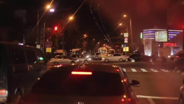 Rostov-on-Don, Rosja - 17 września 2020: Samochody jadą w nocy wzdłuż drogi w mieście i przejeżdżając przez rzędy zaparkowanego samochodu w pobliżu różnych zakładów. Aparat zmienia ostrość. — Wideo stockowe
