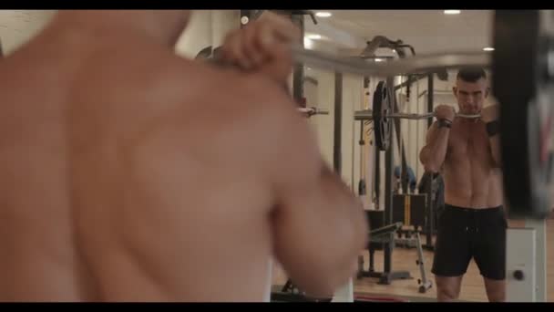 Attraente giovane uomo che si allena in palestra e fa esercizio w-bilanciere con pesanti bicipiti di pompaggio davanti a uno specchio — Video Stock