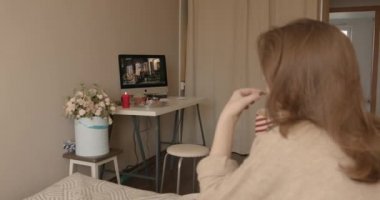 Minsk, Belarus - 17 Eylül 2020: Küçük bir kız sıcak bir yatak odasında köpeğiyle birlikte sıcak bir yatakta oturup kakaolu zencefilli ekmek yiyor ve dizüstü bilgisayarında noel filmi izliyor. Tatil atmosferi