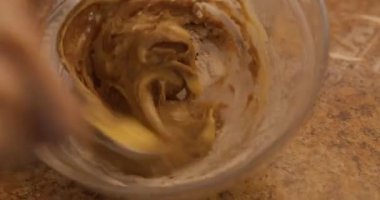 Genç enerjik bir kadın Noel ve yeni yıl için mutfakta zencefilli ekmek pişiriyor ve hamuru cam bir kasede kaşıkla karıştırıyor.