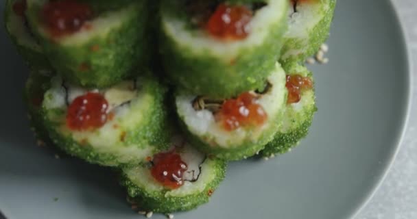 Sushi se zeleným létajícím rybím kaviárem je rozloženo na talíři ve skluzavce se sýrovou hvězdou na vrcholu. Natáčení maker — Stock video