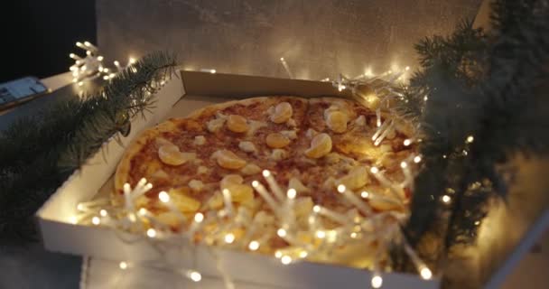 Une jeune fille prend une pizza en tranches avec du salami sur une planche de bois entourée d'une guirlande brûlante. Gros plan — Video