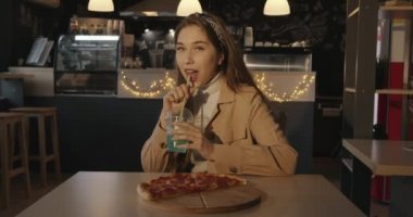 Hayalperest, parlak gözlü genç bir kız kafede lezzetli pizzalarla bir masada oturur ve pipetle kokteyl içer.