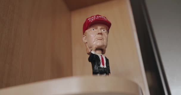 Minsk, Belarus - September 17, 2020: Αγαλματίδιο σουβενίρ του Donald Trump σε κοστούμι με μια κόκκινη γραβάτα και ένα κόκκινο καπάκι στέκεται σε ένα ξύλινο ράφι. Κοντινό πλάνο — Αρχείο Βίντεο