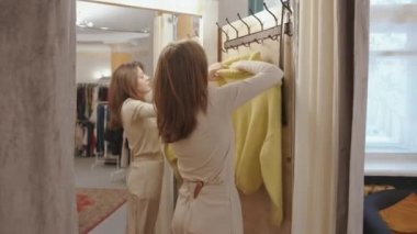 Giyim mağazasında alışveriş yapan ve aynanın önünde soyunma odasında süveter deneyen hoş bir genç kız.