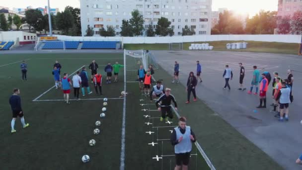 Misk, Belarus - 15 augustus 2020: Drone-beelden van een voetbalteam training in het stadion op een zomerdag. Spelers springen over voetbalballen en slagbomen — Stockvideo