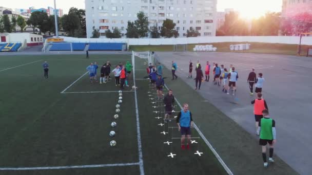 Misk, Vitryssland - 15 augusti 2020: Ovanifrån av fotbollslag träningspass på stadens stadion på en sommarkväll. Spelare hoppar över barriärer — Stockvideo