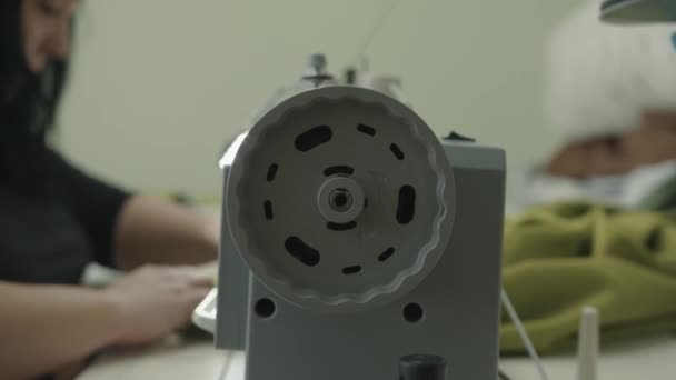 A young woman sews fabric parts in a furniture repair workshop. Side view of the flywheel of a professional sewing machine — Stock Video