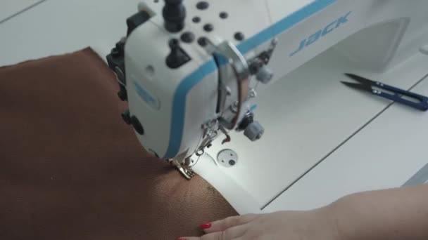 Misk, Bielorrusia - 15 de mayo de 2020: Vista superior de las manos de las mujeres cosiendo detalle de la tela en la máquina de coser profesional en el taller de reparación de muebles tapizados — Vídeos de Stock