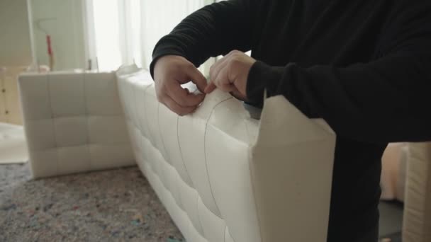 Een professionele vakman verwijdert nietjes van bankonderdelen in een meubelreparatie- en stofferingswerkplaats — Stockvideo
