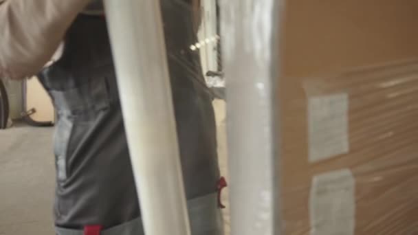 Misk, Weißrussland - 15. Mai 2020: Ein Mann arbeitet in einer Werkstatt für die Reparatur und Restaurierung von Polstermöbeln und wickelt das fertige Produkt mit Polyethylenfolie ein — Stockvideo