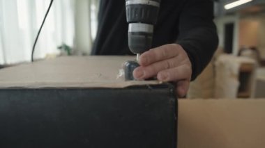 Adamın biri atölyede çalışıyor ve eski döşemeyi değiştirmek için elektrikli tornavidayla mobilyadaki tüm parçaları söküyor.