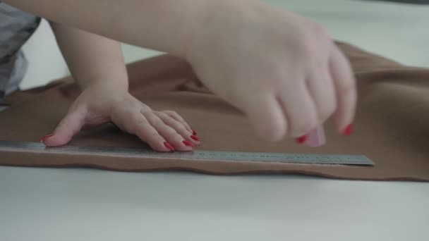 Жінка працює в майстерні по ремонту м'яких меблів і малює лінію на тканині з крейдою під лінійкою — стокове відео
