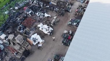 Elinde not defteriyle depodaki yedek parçaların arasında yürüyen genç oto tamircisinin en iyi görüntüsü.