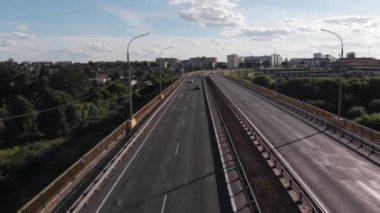 Nehir üzerindeki yol köprüsündeki trafiğin hava görüntüsü. Kıyıda siyah su ve yeşil ağaçlar var.
