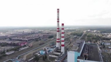 Şehrin çevresindeki sanayi binaları, bacaları ve soğutma kuleleri olan bir termik santralin insansız hava aracı görüntüleri.