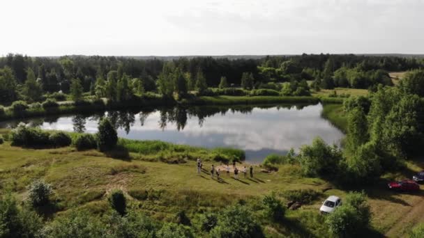 Tiroteio com quadricóptero um grupo de pessoas de um pé na margem de um lago e o reflexo das nuvens em um dos lagos — Vídeo de Stock