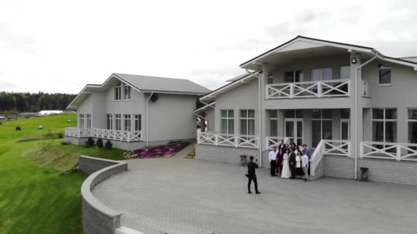 Misk, Vitryssland - 15 augusti 2020: Ovanifrån fotografering av brudgummen och nevy med gäster som står på trappan till ett vackert hus på landet på en sommardag — Stockvideo