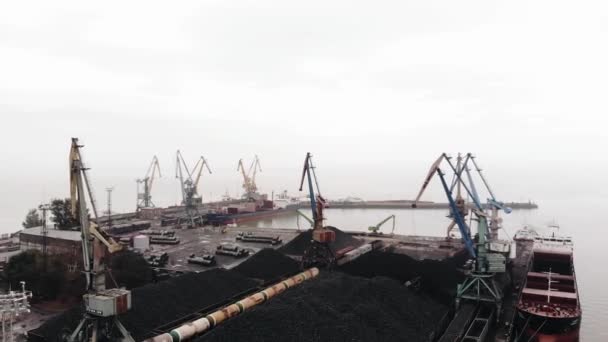 Вид с воздуха на морской порт с вышковыми кранами, загружающими уголь в поезда и танкеры с грузом на воду — стоковое видео