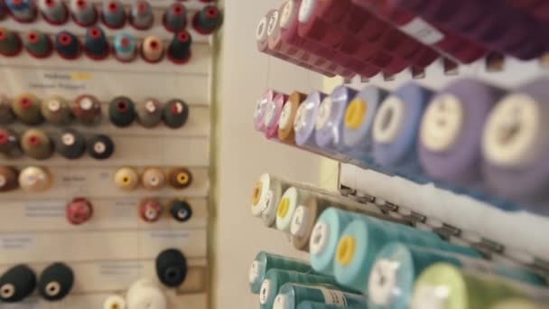 縫製工場の巨大なスタンドにミシン糸のスプールの行は、カラーマッチングされています — ストック動画