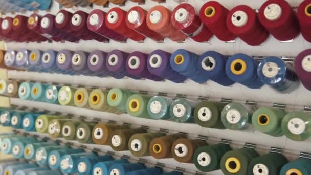 Vista superior de filas de carretes de hilo para máquinas de coser combinadas por colores y tonos en un taller de producción o taller — Vídeos de Stock